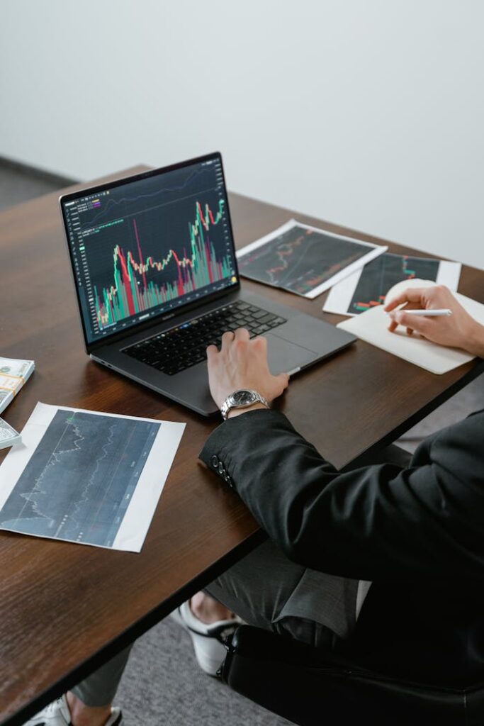 A business analyst reviewing stock charts on a laptop, analyzing market trends.